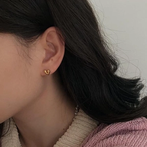 Close-up of a model wearing a golden 925 sterling silver heart-shaped stud earring