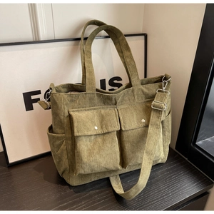Detail view of olive green corduroy tote bag featuring two front flap pockets and adjustable strap