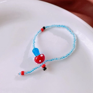 Detail of handmade beaded necklace with glass mushroom charm and blue seed beads