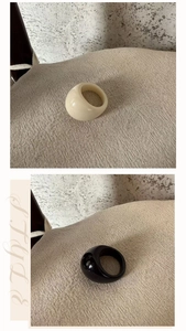 Detail of minimalist chunky oval resin rings in black and cream on textured background