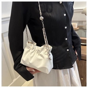 Detail of white pleated bucket bag with silver metal chain strap and decorative ball