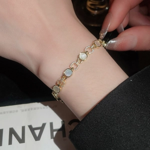 Gros plan d'un bracelet doré avec disques en nacre et cercles sertis de zircons