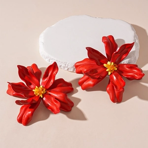 Macro view of artistic red acrylic flower earrings with yellow beads on stone base