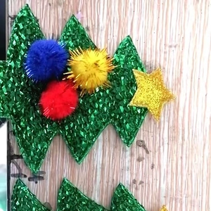 Glittery Christmas tree craft accessory with colorful pom poms on wooden background