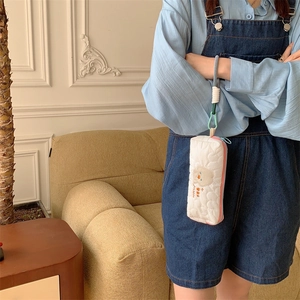 Quilted white bag detail featuring cute bear embroidery and a dual-color woven wrist strap