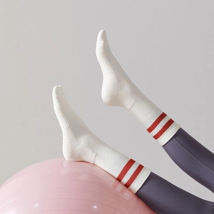 Close-up of white cotton yoga toe socks with red stripes on a pink yoga ball