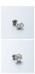 Macro detail of planet heart and clover zircon earrings in polished titanium steel