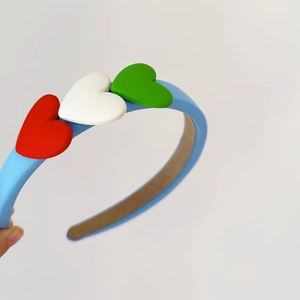 Detail of blue fabric headband featuring three colorful heart shapes held by a hand