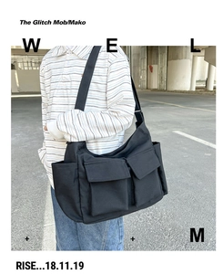 Street style shot of a black large canvas messenger bag with double front utility pockets