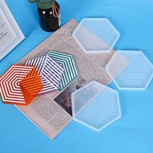 Macro shot of hexagon silicone mold and geometric striped resin coasters on blue surface
