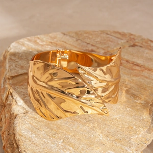 Macro detail of golden leaf cuff bracelet with realistic vein textures on rock base