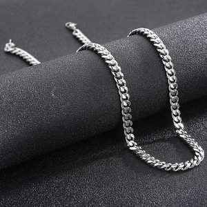 Close-up of a polished silver Cuban link chain necklace on a black textured background