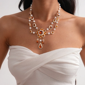 Detail of vintage gold necklace featuring amber crystals and layered faux pearls