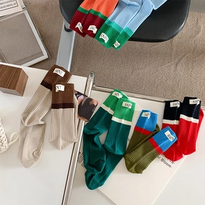 Close-up of colorful color-blocked crew socks with SAINT woven label on the cuff