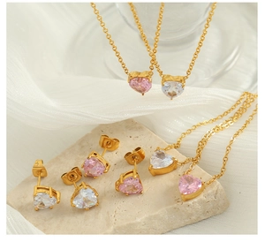Close-up of pink heart pendant necklace and matching zircon earrings on silk backdrop