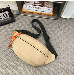 Detail of beige waterproof crossbody bag featuring orange zipper and black nylon strap