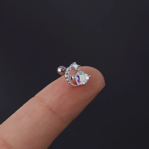 Detailed macro view of heart and moon stud earring on finger showing small scale and zircon