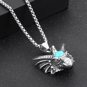 Macro detail of silver dragon pendant with inlaid turquoise on black textured surface