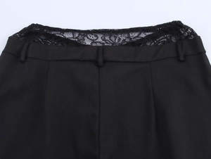Detail of black pants featuring lace拼接 at the waist with belt loops on a white background