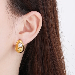 Close-up of a gold water-drop earring with a white pearl on a female model