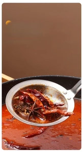Detail view of fine mesh stainless steel skimmer filtering spices from hot pot soup