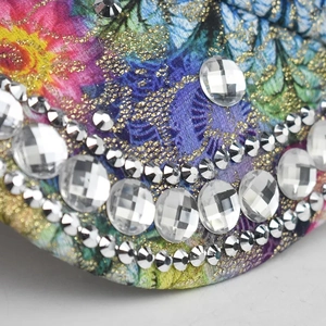 Detail of leaf print baseball cap with butterfly pattern and sparkly rhinestones decoration