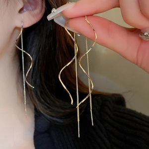 Macro shot of minimalist wavy geometry earrings in gold and silver metallic finish