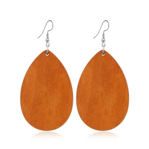 Détail de boucles d'oreilles en bois marron en forme de goutte sur fond blanc pur