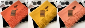 Detail showing thick orange and yellow tassel scarves with leather brand tags and fringe