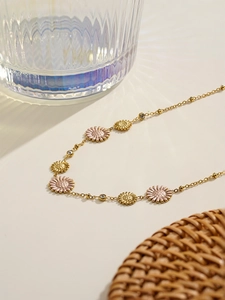 Detail of 18K gold-plated necklace with pink and gold daisy pendants and beads