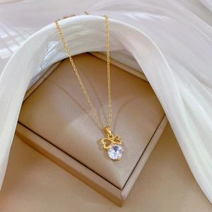 Elegant gold bow necklace with sparkling zircon pendant on white silk background