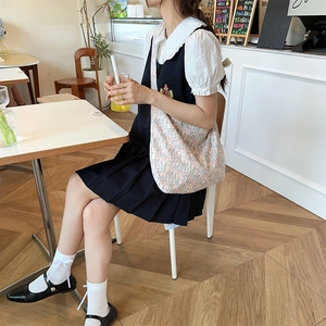 Japanese style pleated pinafore dress paired with a floral canvas shoulder bag in a cafe