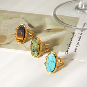 Detailed close-up of oval tiger eye and turquoise rings with hammered gold bands