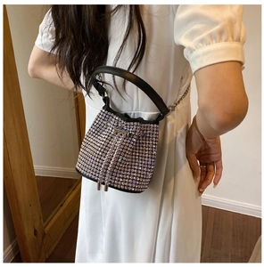 Detail showing shiny silver rhinestone bucket bag with black handle and chain strap on model