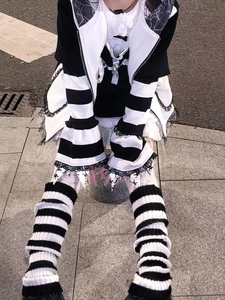 Detail of gothic black and white striped leg warmers with lace trim and skull charms