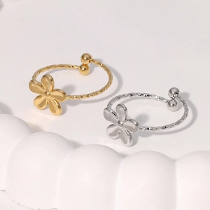 Minimalist gold and silver flower rings in adjustable open design on ceramic tray