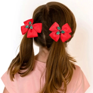 Detail of red Christmas hair bows with holly leaf sequins on girl's pigtails