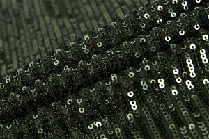 Close-up of deep green sequin fabric showing reflective details and texture of the dress