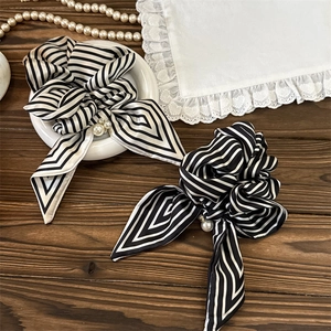 Elegant black and white striped scrunchie with pearl detail on a rustic wood background