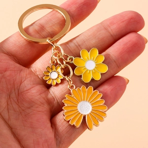 Floral daisy keychain with white and yellow enamel charms on a gold metal ring