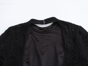 Detail of elegant black dress showing wavy textured fabric and hollowed neckline closure