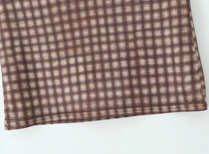 Vista detallada de las costuras y la textura de la tela de cuadros marrones de la falda