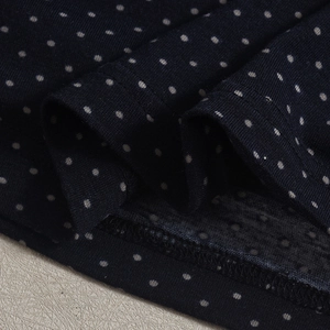 Gros plan du tissu à pois bleu marine montrant les coutures fines et la texture jersey