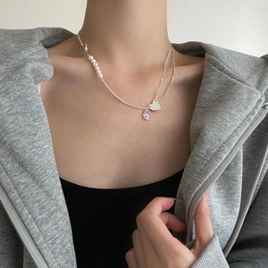 Detail showing asymmetrical 925 silver necklace with white pearls and heart pendant