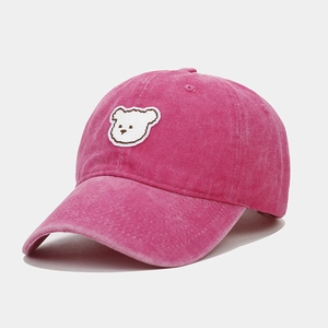 Close-up of cute white bear embroidery on a vintage washed rose pink baseball cap texture