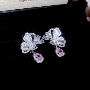 Macro shot of silver butterfly earrings with pink teardrop gems on black velvet