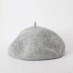 Close-up of light gray wool fabric texture and stitching on the minimalist beret hat