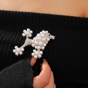 Detail of a vintage poodle brooch with pearls and rhinestones on black knitwear