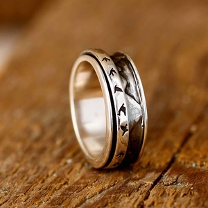 Macro shot of mountain range and flying bird carvings on the vintage silver spinner ring