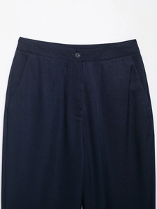 Detailed close-up of dark blue tailored trousers showing twill fabric texture and waist button